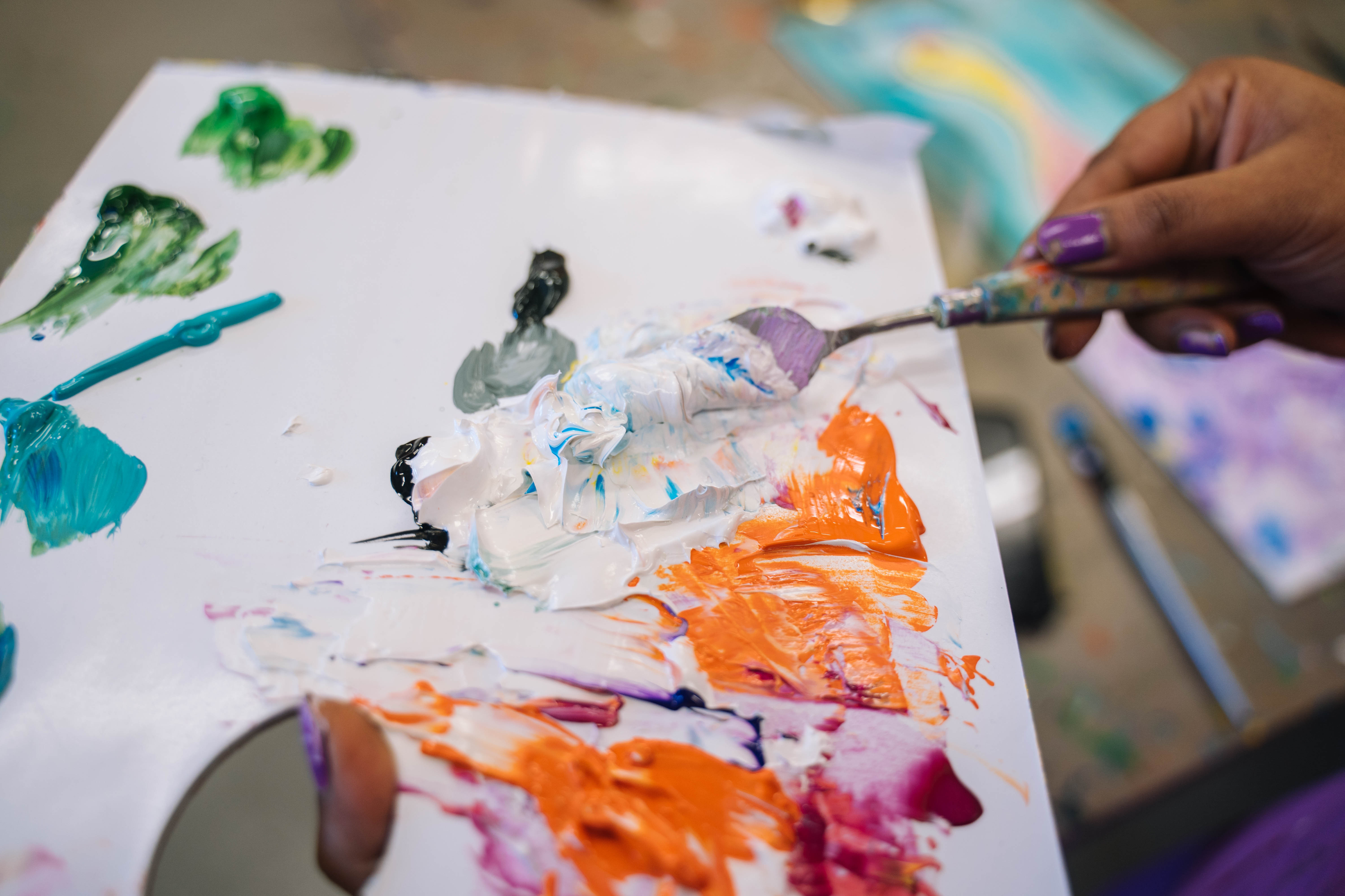 Person thickly applying acrylic paint to a canvas